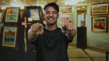 Bir sanat galerisindeki genç adam coşkuyla canlı tabloların arasında, bağlılık ve neşe hissi ile canlı bir iç mekan atmosferi yaratıyor..