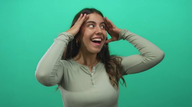 Genç İspanyol kadın, izole edilmiş yeşil arka plan duvarı için heyecanını dile getiriyor.