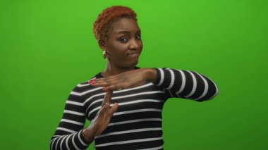 Yeşil stüdyo ortamında elleri olan bir kadın mola hareketi yapıyor; ciddi yansımayı duraklat.