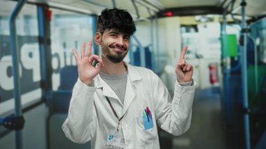 Otobüsün içinde jest yapan genç adam otobüsün camlarının önünde otururken kendinden emin ve neşeli bir görünüm sergiliyor..