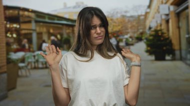 Genç İspanyol kadın şehir manzarası, ağaçlar ve insanlarla çevrili hareketli bir caddede dışa dönük tepkisini açık bir ortamda yakalayarak reddediyor..