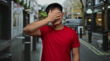 Kırmızı gömlekli genç adam şehir caddesinde bir şehir manzarasını neşe içinde resmediyor..