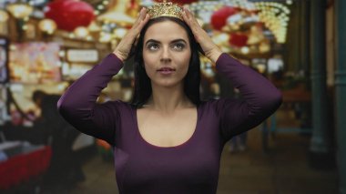 Genç İspanyol kadın açık havada tacı rengarenk şehir zeminiyle ve parlak asılı ışıklarla ayarlıyor.