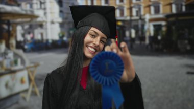 Mezuniyet şapkası takan, elinde mavi kurdele olan bir kadın.