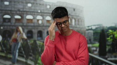 Roma 'daki tarihi Roma Kolezyumu' nun önünde tefekkür eden genç adam.