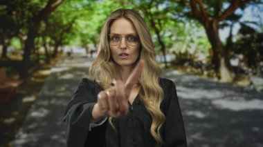 Hakim üniformalı kadın yeşil ağaçlar ve arka planla açık hava parkında güvenle duruyor.