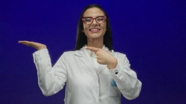 Beyaz üniformalı İspanyol kadın bilim adamı, laboratuvar ortamında heyecan ve coşku sergileyen canlı mavi bir duvarı avucunun içine alıyor..