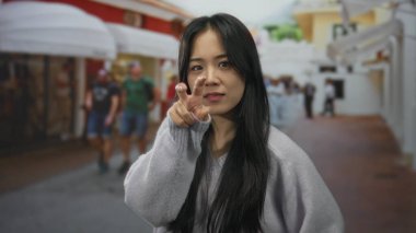 Şehir merkezindeki kalabalık caddede Çinli kadın dikkatli bir el hareketi yapıyor..