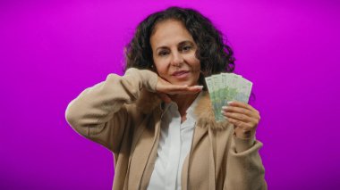 Romen banknotlarını elinde tutan orta yaşlı bir kadın canlı bir mor arka plana karşı, neşeli bir ifadeyle para sergiliyor..