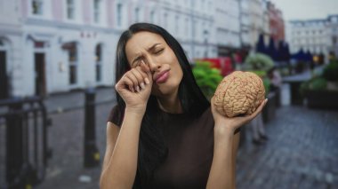 Sokakta elinde hüzünlü bir ifadeyle gezen genç bir kadın stres ya da kafa karışıklığına işaret ediyor..