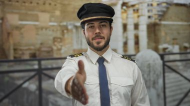 Üniformalı genç adam güneşli bir günde dışarıda mimari arka plana karşı tokalaşıyor.