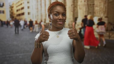 Afrika kökenli Amerikalı bir kadın, tarihi bir binanın ön cephesine el sallayarak el kol hareketi yapıyor..