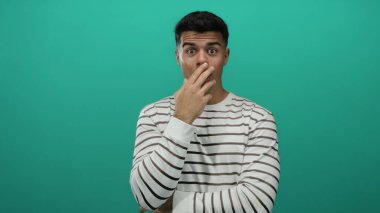 Çizgili genç adam yeşil arka plana şaşırmış görünüyor, izole edilmiş bir portre ortamında gizemli bir şekilde modern ve temiz bir stil sergiliyor..