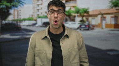 Sokak ortasında, İspanyol asıllı ve genç bir adamın açık hava sahnesinde sıradan kıyafetlerle durduğu yerde adam samimi bir gülümseme içinde ortaya çıkıyor..