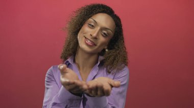 Bir stüdyo ortamında bakarken avuçlarını uzatan ve nazikçe gülümseyen kadın; nezaket dinginliğine hoş geldin..