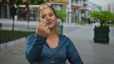 Sokak kaldırımında iki eliyle parmakla gösteren bir kadın. Mavi ceketli, gülümseyen bir kadın..