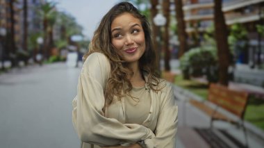 Güneşli bir sokakta, açık havada gülümseyen bir kadın. Palmiye ağaçları gençlik mutluluğunu yakalıyor ve canlı bir şehir ortamında rahat bir zarafeti yakalıyor..