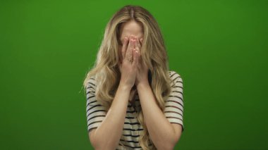 Yeşil ekran setinde, yeşil izole edilmiş arka plan duvarı karşısında genç sarışın modelin yer aldığı kadın yüzü hayal kırıklığını gösteriyor..
