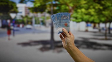 Kentsel sokak ortamında Malezya halkaları tutan adam, finans ve bankacılık odaklı iş ve döviz alışverişini resmediyor.