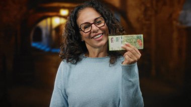 Bir şehir caddesinde elinde Arjantin pezosu tutarken gülümseyen bir kadın, canlı bir fon ile finansal temalar sergiliyor..