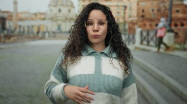 Roma harabelerinde duygularını ifade eden kadın, arka planda gündüz vakti antik mimariyle birlikte caddeyi yıkıyor..