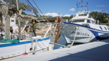 Mallorca 'daki Cala Figür Limanı' na demirli teknelerin bulanık görüntüsü, açık mavi gökyüzünün altındaki marinanın doğal güzelliğini vurguluyor..