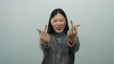 Beyaz arka planda kaba bir jest yapan bir kadın meydan okuduğunu ve neşeli bir ifadeyle gündelik kıyafetlerini giydiğini ifade ediyor..