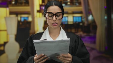 Hakim üniformalı İspanyol kadın şık otel iç mekanlarında doküman okuyor, profesyonellik duygusunu aktarıyor ve şık ortamın ortasına odaklanıyor..