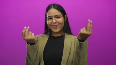 Latin kökenli genç bir kadın, soyutlanmış pembe arka plana karşı para hareketinde bulundu..