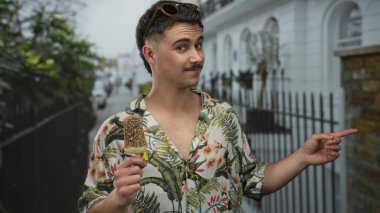 Genç İspanyol bir adam şehirde dondurma yiyor. Çiçekli gömlek ve güneş gözlüğü takıyor. Açık havada neşeli bir turist havasını kucaklıyor..