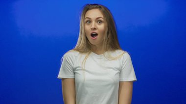 Canlı mavi bir arka plana karşı şaşkınlığını ifade eden kadın, beyaz bir gömlek giyiyor, gençlik enerjisini ve duygusunu basit ama çarpıcı bir görsel kompozisyonda somutlaştırıyor..