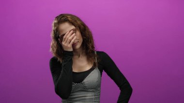 İzole edilmiş pembe arka plan duvarının önünde yorgunluğunu ifade eden bir kadın stüdyo ortamında duygusal yorgunluk gösteriyor..