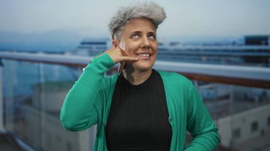 Yeşil kazak giyen kadın, bina üzerinde parmak ile el işareti gösteriyor; oyuncu bağlantı.