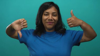 Kadın parmaklarını yukarı kaldırır ve baş parmağını aşağı tutar gözleri kapalıdır ve tatlı bir gülümseme sergiler.Kararsızlık.