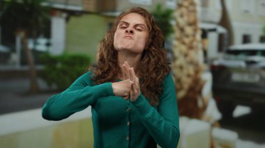 Şehir sokaklarında sinirli, kıvırcık saçlı yeşil tişörtlü, şehir planıyla çevrili duyguları ve ifadeleri yansıtan bir kadın..