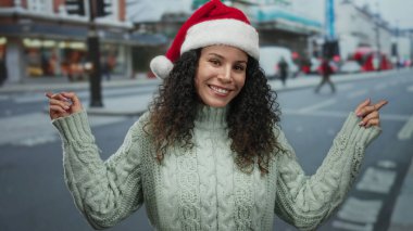 Noel Baba şapkası ve süveteriyle gülümseyen bir kadın kalabalık bir caddede festival sezonunda birden fazla yönü işaret ediyor..