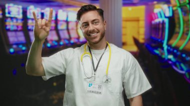 Genç sakallı doktor, steteskopla canlı kumarhane ortamında taş jestler yapıyor, sağlık ve eğlence sektörünün canlı bir karışımını yakalıyor..