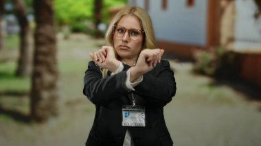 Gözlüklü bir kadın taş avluda dikiliyor. Kapalı gözlerle, sarı saçlarla, kimlik kartlarıyla, Akdeniz arka planında onaylamadığı şeyleri gösteriyor..