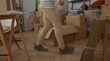 İspanyol adam yeni bir evin içinde görünür mobilyalar ve aksesuarlarla kutular düzenliyor. Bu da oturma odasında taşınma ve yerleşmeyi öneriyor..