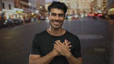 Alacakaranlıkta kalabalık bir şehir sokağının önünde siyah tişört giyen İspanyol bir adam..