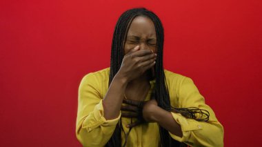 Ağzı kaplayan kadın kırmızı arka planda sarı bluz giymekten rahatsız görünüyor. Duygularını ve renklerini canlı bir şekilde aktarıyor.