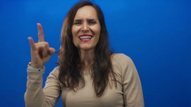 Stüdyoda kaya boynuzları gösteren genç İspanyol kadın eli kendine güvenen bir ifadeyle; rock eğlence isyanı.