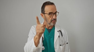 Gözlük takan ve steteskop takan doktor beyaz bir arka plana karşı yoğun bir şekilde kamerayı işaret ederek profesyonelliği, konsantrasyonu ve otoriteyi somutlaştırıyor..