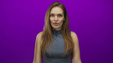 Mor arka planı olan bir stüdyoda eli alnında ve geniş gözlü genç bir kadın. Sürpriz..