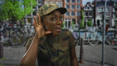 Kamuflaj üniformalı kadın asker, şehir caddesinde kulağı kulaklarında künye takıyor, disiplin görevine hazır..