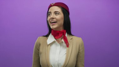 Uçuş görevlisi üniformalı İspanyol kadın canlı mor bir arka plana karşı tutkuyla el kol hareketi yapıyor, dinamik duygular ve profesyonellik taşıyor..