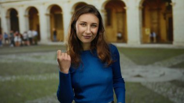 Mavi gömlekli bir kadın, eski üniversitede kemerli taş mimarisi ile içeride dururken Avrupa 'da tarihi bir akademik ortamı işaret ediyor..