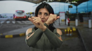 Kadın, açık hava havaalanı terminalinde çapraz kollarıyla inkar jesti yapıyor..