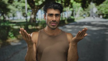 Genç İspanyol adam, yeşil ağaçlar ve güneş ışığında asfalt ile çerçevelenmiş caddelerde palmiyelerini silkeliyor..