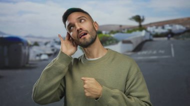 Genç İspanyol bir adam, hareketli bir şehir caddesinde pozitif bir açık hava enerjisiyle canlı bir şehir atmosferini yakalarken, dikkatle bir jest yapıyor..